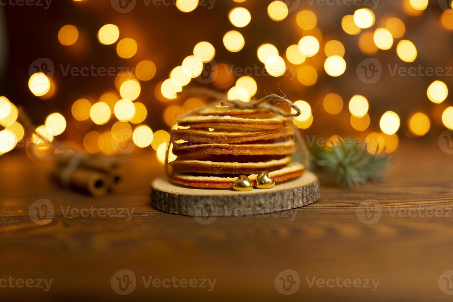 Two golden hearts lie nea the bunch of dried oranges with bokeh lights on the background photo