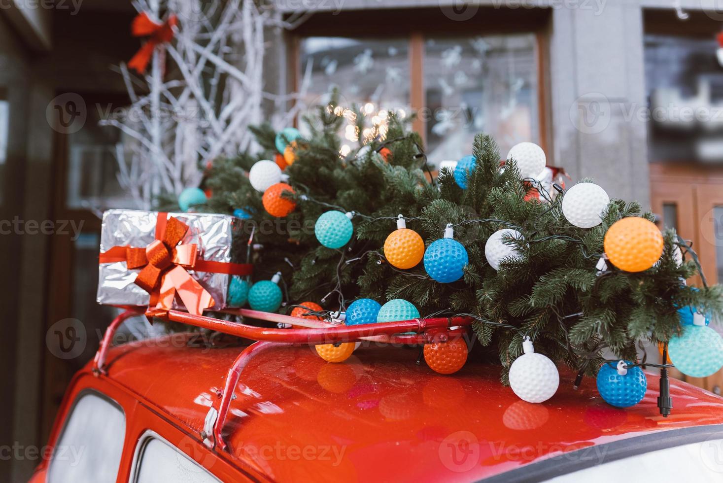 Red retro car with a Christmas tree fir tied to the roof. photo