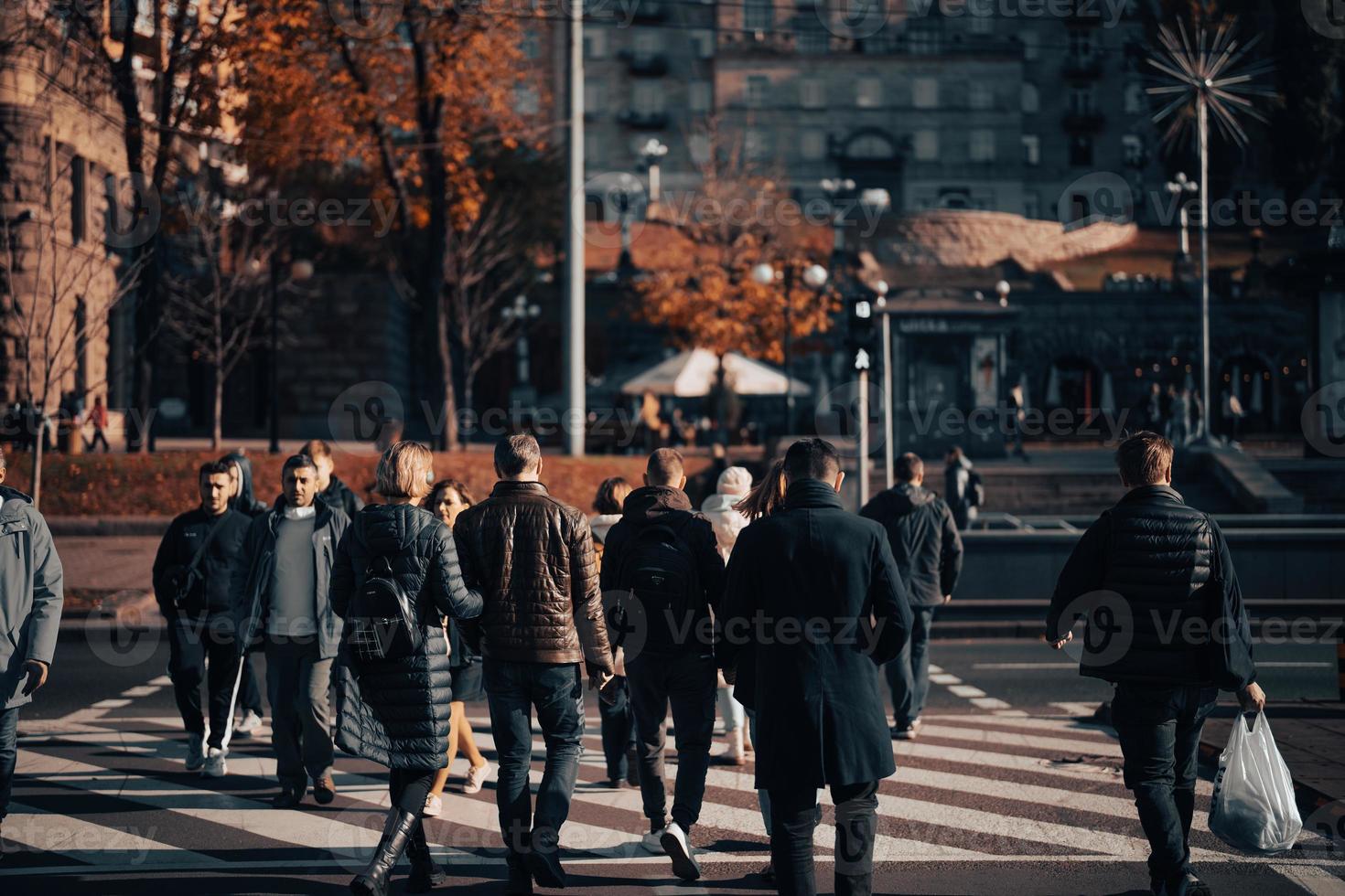 Lots of people crossing the street at the traffic lights. photo