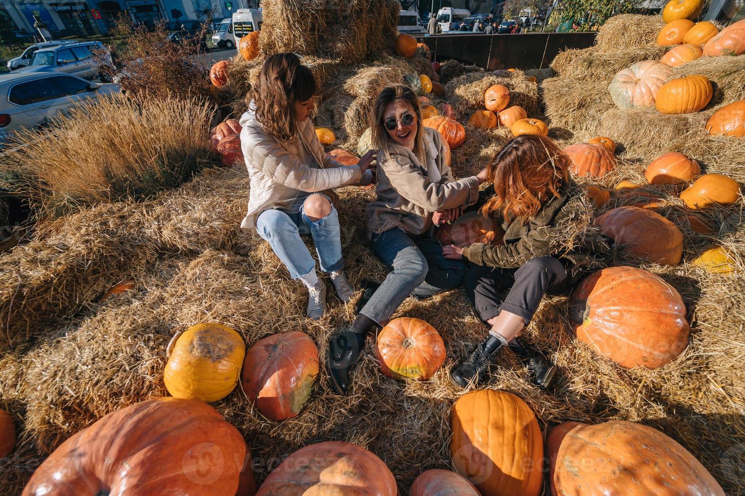 Young girls lie on haystacks among pumpkins. photo