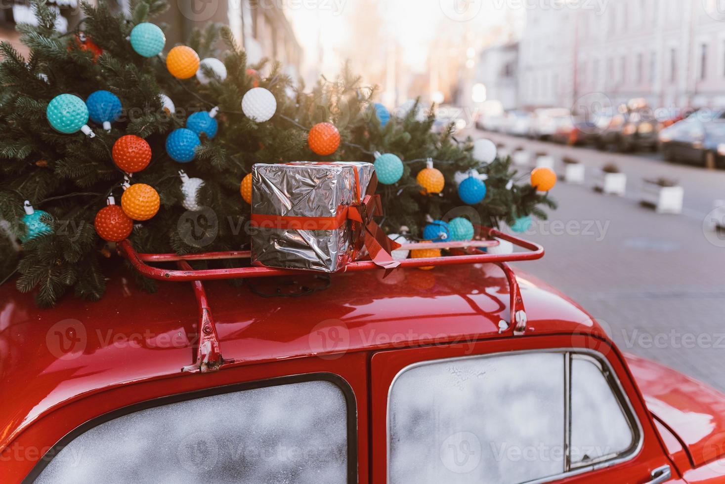 Red retro car with a Christmas tree fir tied to the roof. photo