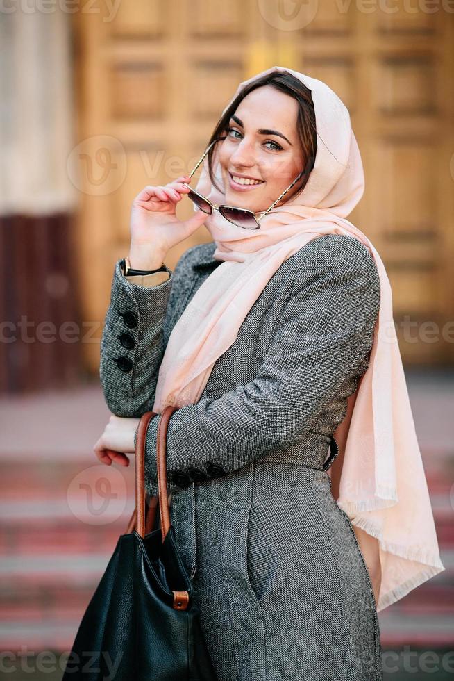 girl in a coat posing on building background photo