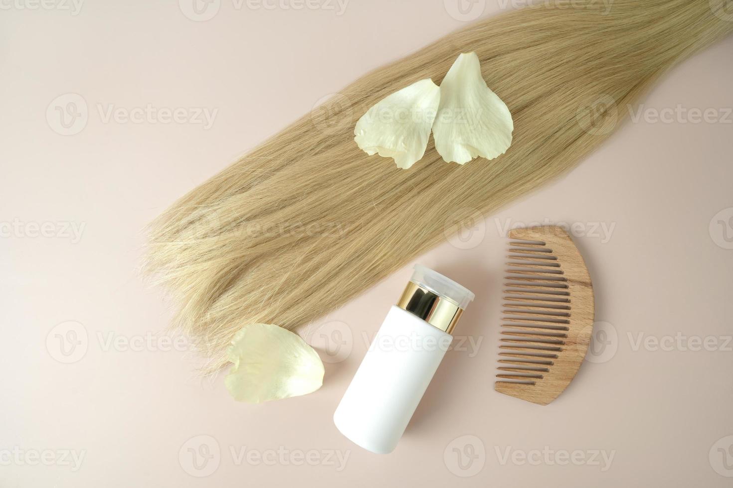 A strand of blonde hair, a dropper bottle of natural essential oil for hair treatment photo