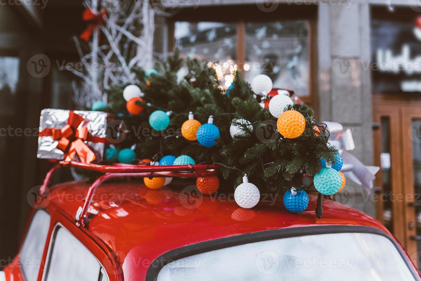 Red retro car with a Christmas tree fir tied to the roof. photo