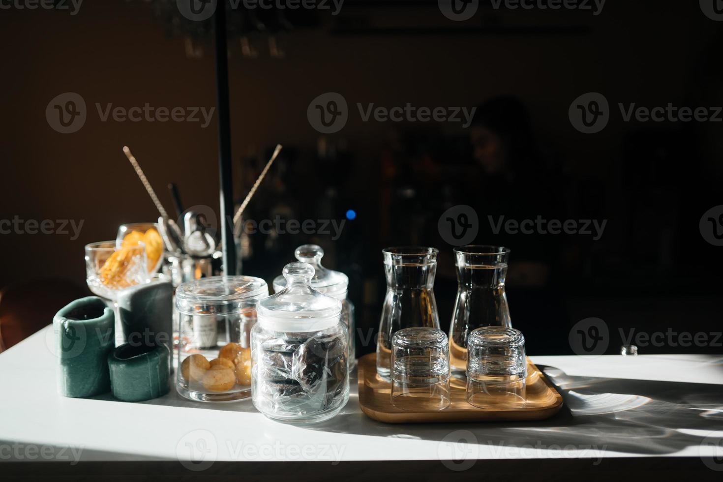 Four glass cups on the bar counter with serving accessories. photo