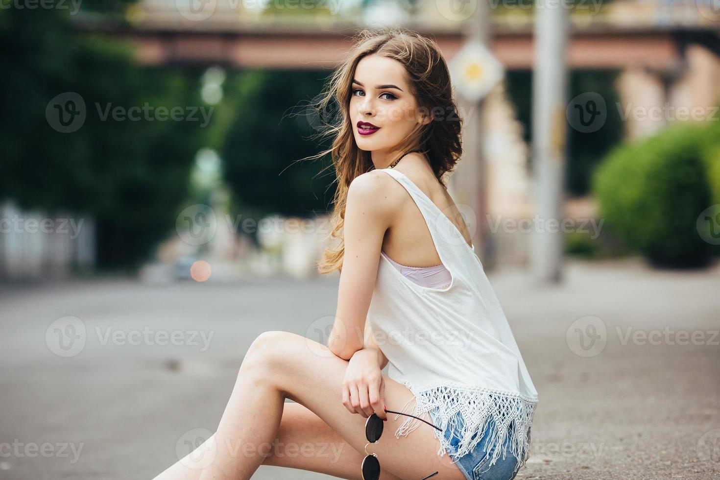 pretty girl sitting in a city street photo