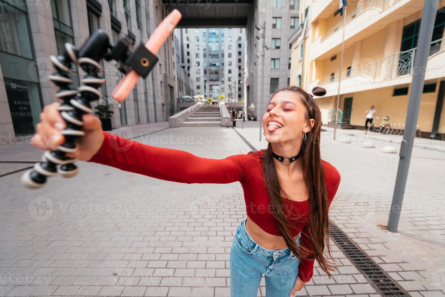 Young female blogger with smartphone streaming on the street. photo
