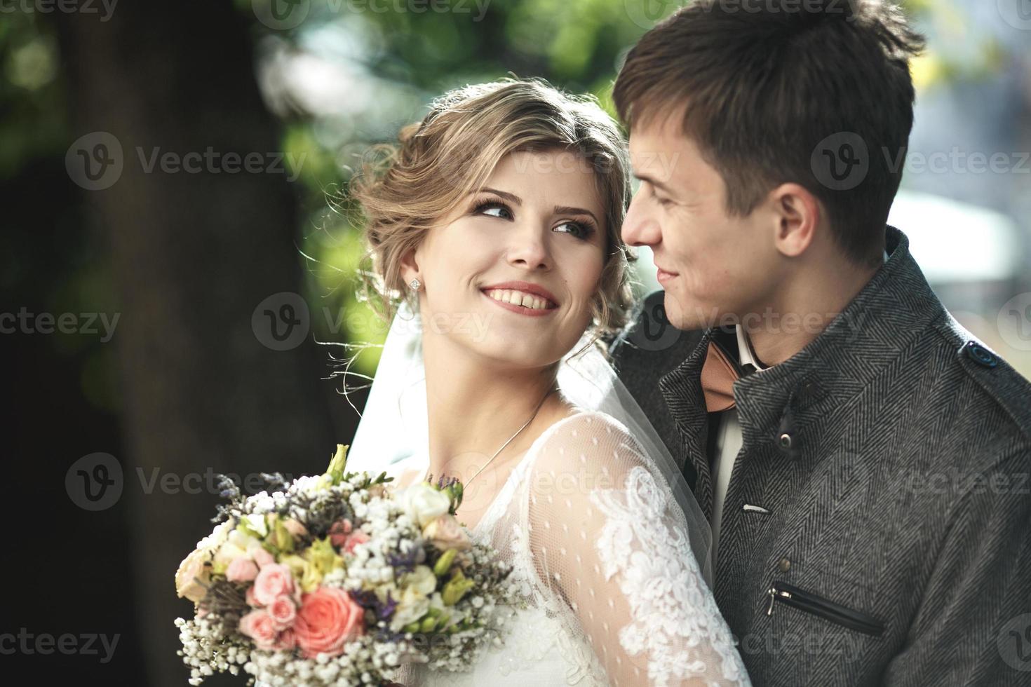 Groom hugs bride photo