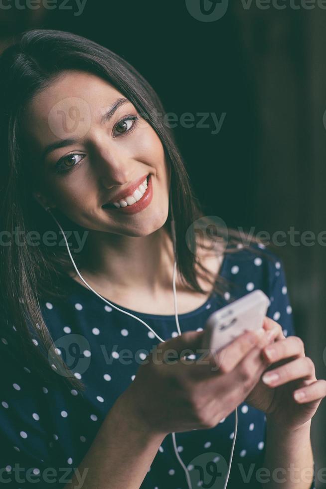 Beautiful girl listening to music on the phone with headphones photo