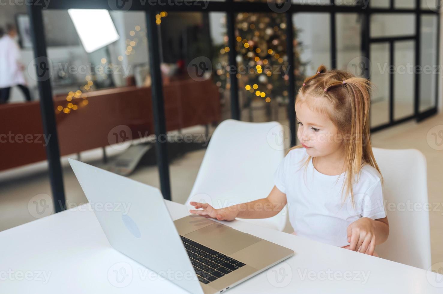 Little girl using tablet computer sitting at table photo