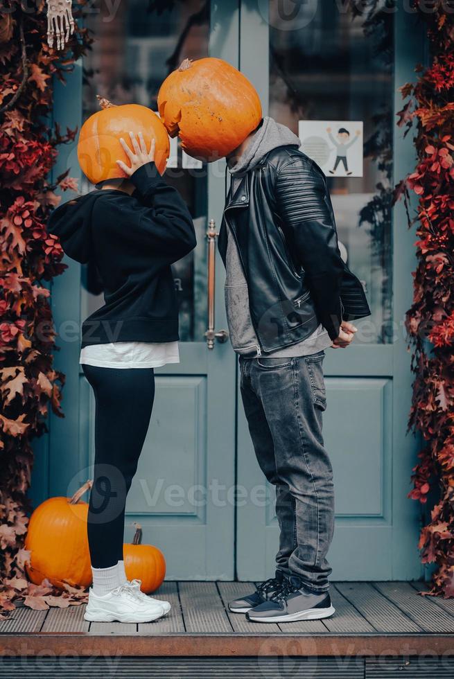 Couple with pumpkin heads posing on camu at the building photo