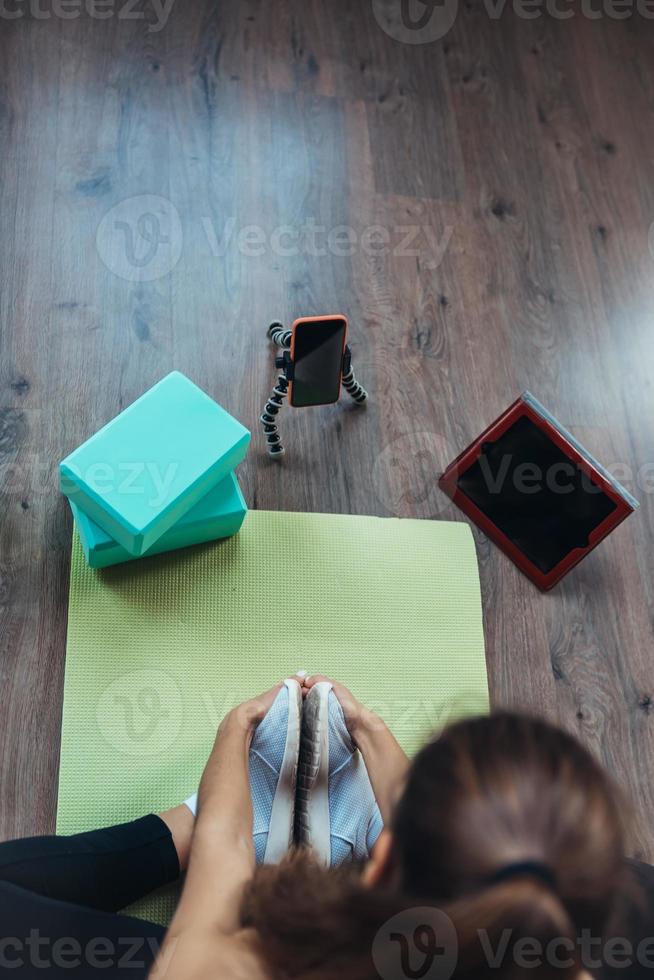 Young woman practicing yoga, is engaged with the teacher online. photo