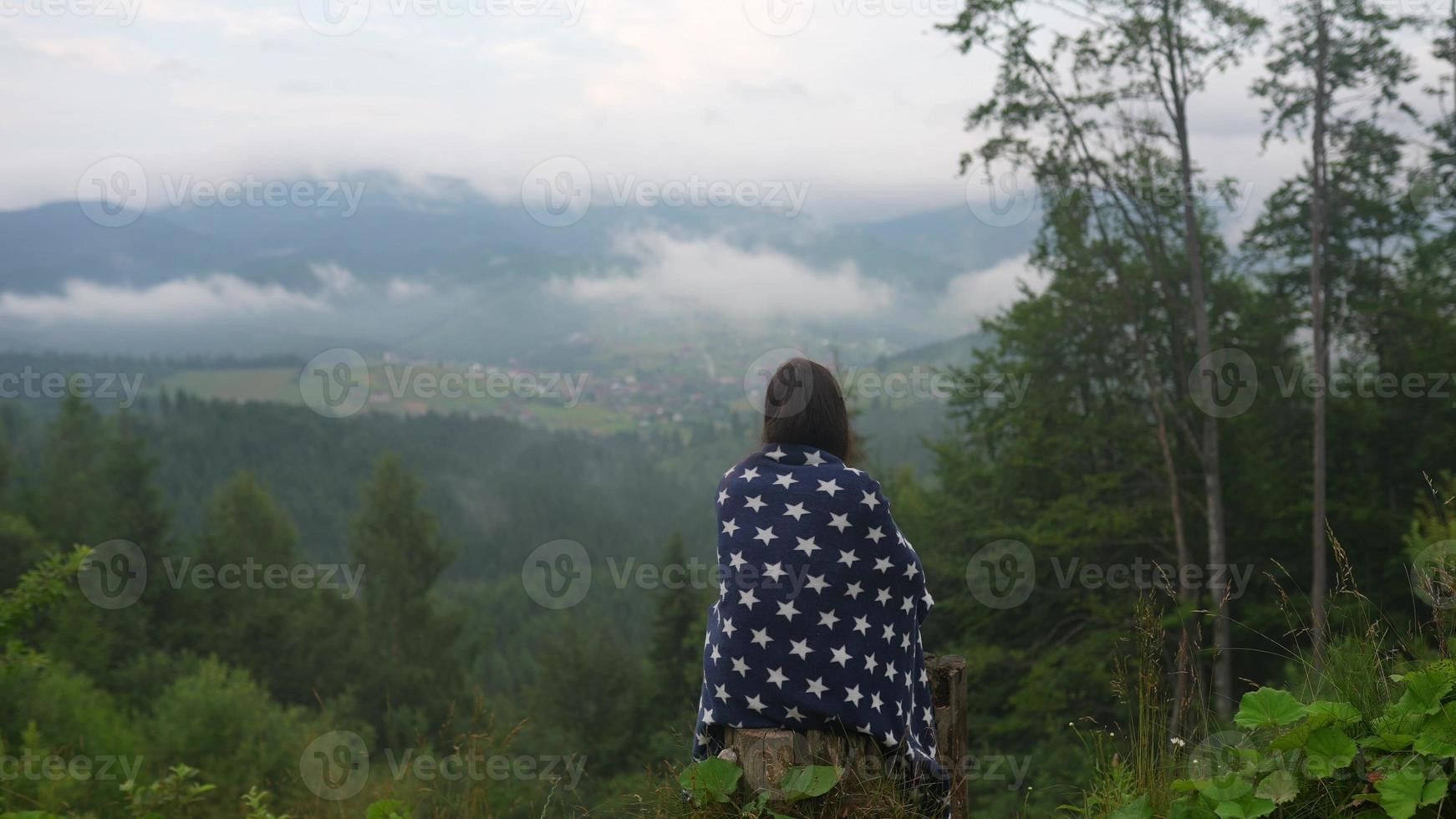 Woman on top of a hill, against the background of a valley photo