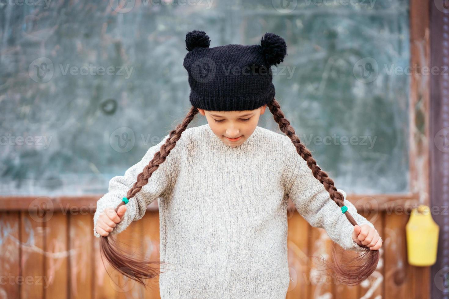 Little girl in a hat posing on the background of the school blackboard photo
