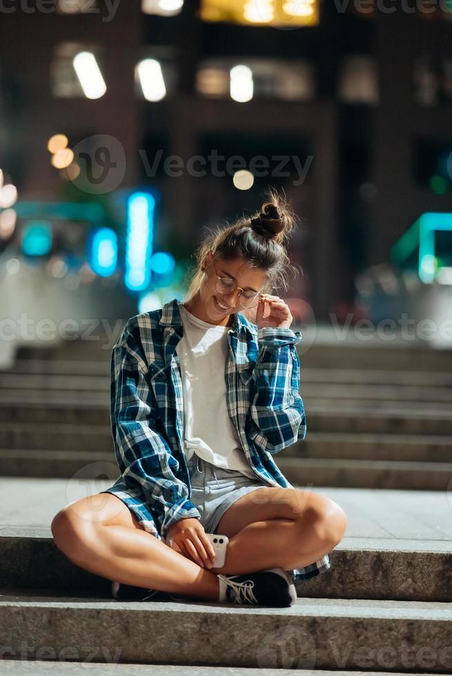 Woman sits on long stone steps in the night city photo