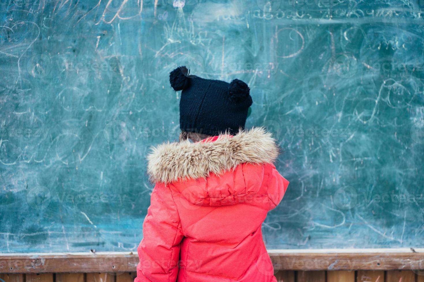 Little girl in autumn park stands at the school board. photo