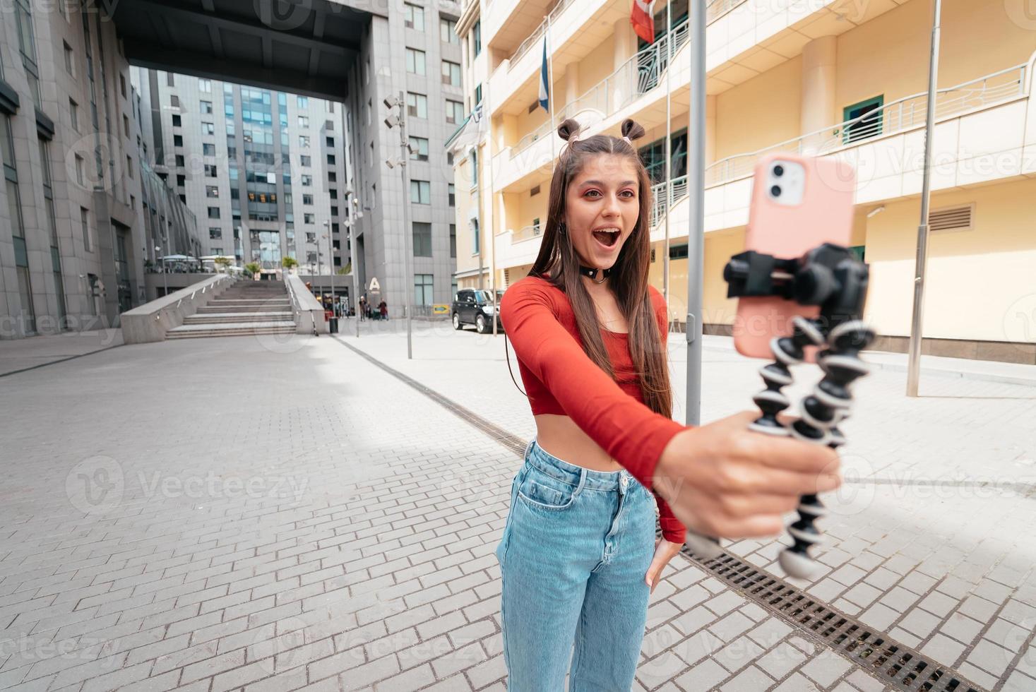 Young female blogger with smartphone streaming on the street. photo