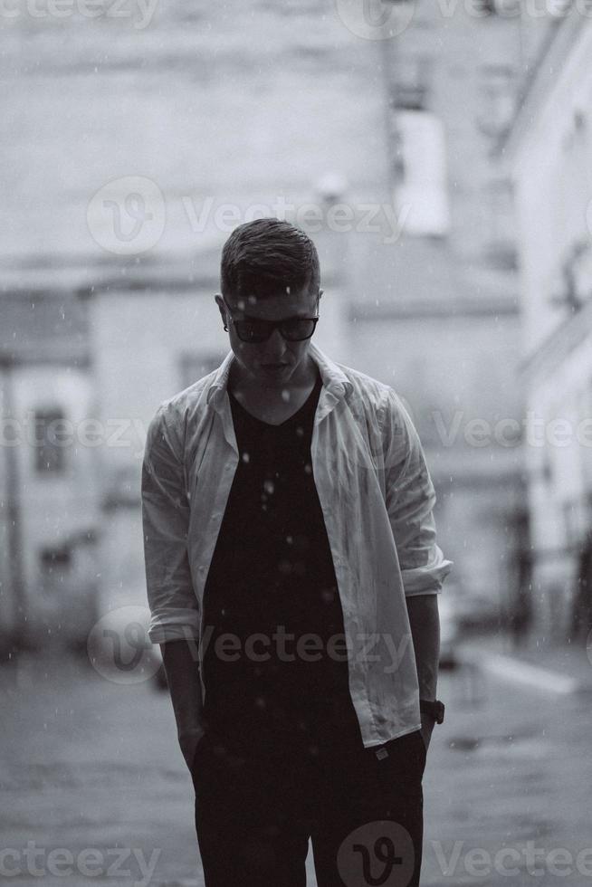 Portrait of carefree handsome young man is feeling free under the rain photo