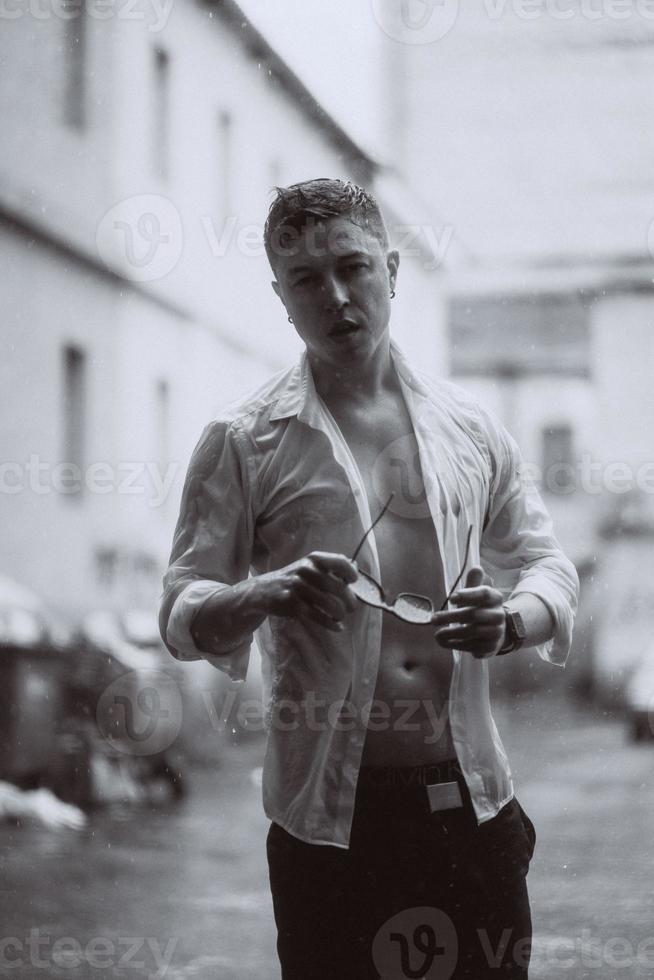 Portrait of carefree handsome young man is feeling free under the rain photo