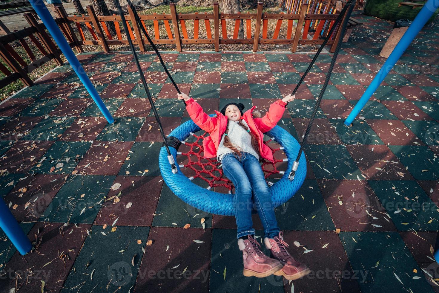 Happy child girl on swing. Little kid playing in the autumn pack. photo