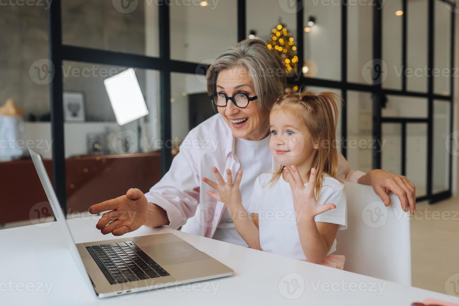 niño y abuela mirando la cámara con laptop foto