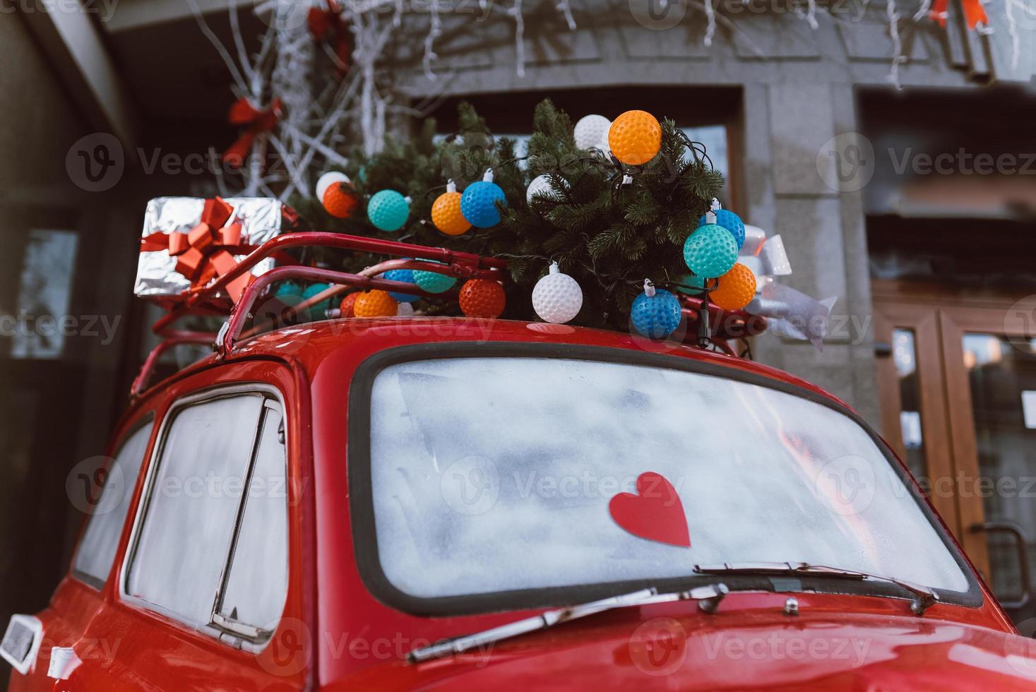 Red retro car with a Christmas tree fir tied to the roof. photo