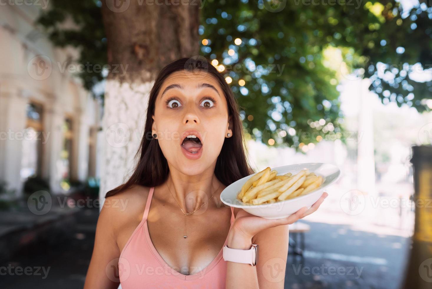 Young women hold french fries on white plates. Street cafe photo