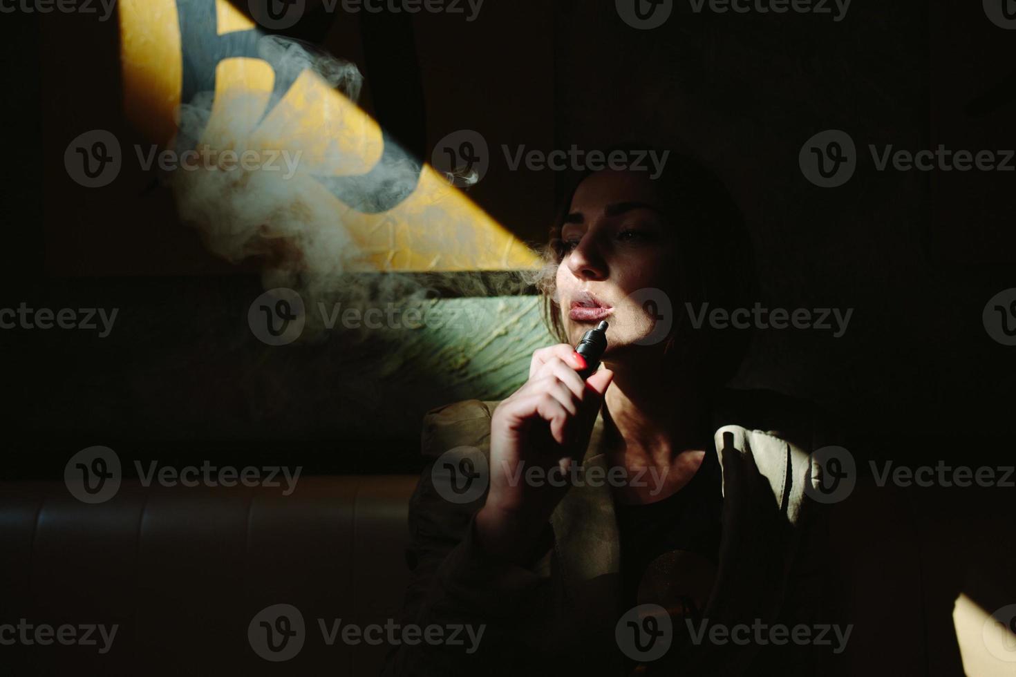 girl sits and smokes electronic cigarette photo