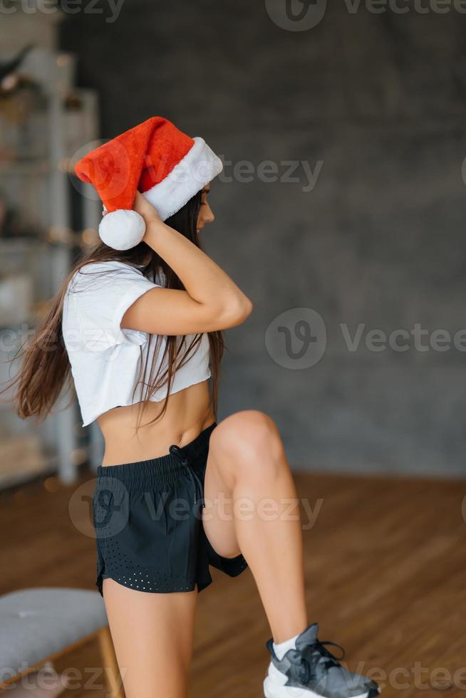 Young woman in santa hat practicing sport gymnastic exercises photo