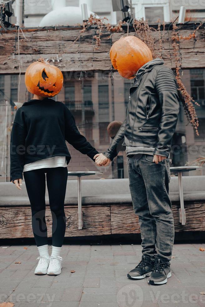 A guy and a girl with a pumpkin heads. Couple holding hands photo