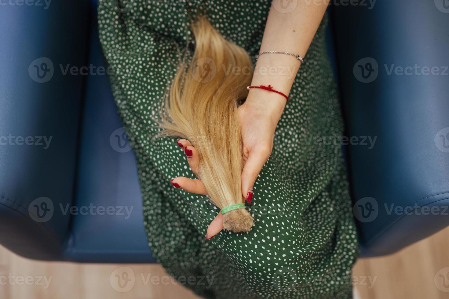 young woman holding her freshly cut long brown hair in pony-tails photo