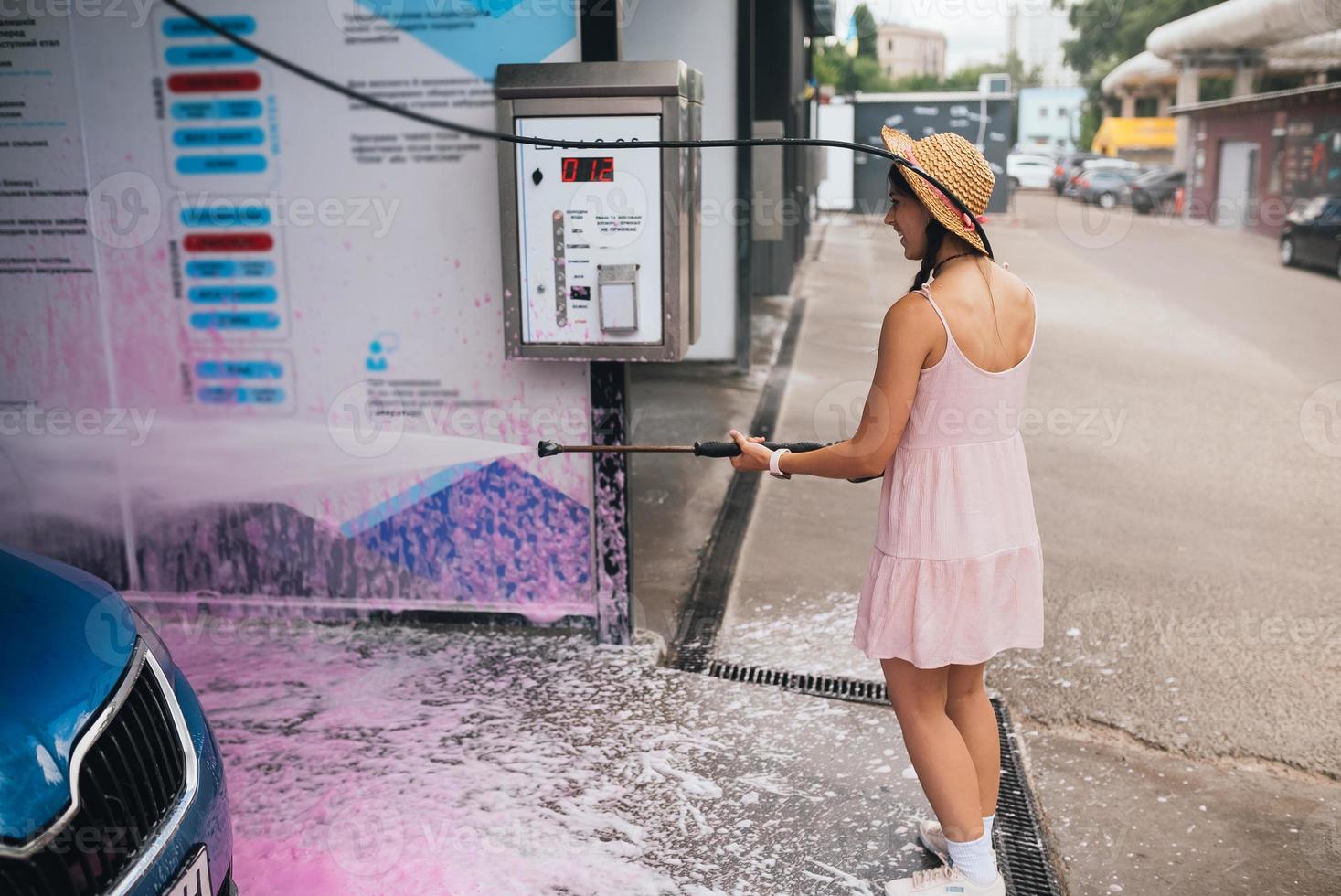 Brunette from a high-pressure hose washes the car photo