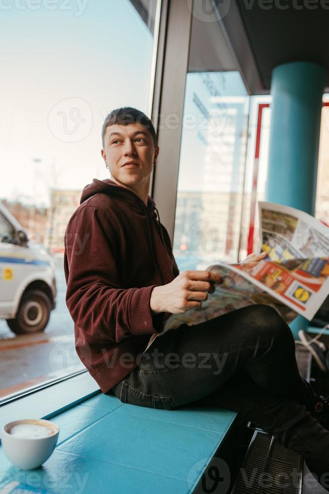 retrato de un hombre sentado en un café, leyendo periódicos y bebiendo café foto