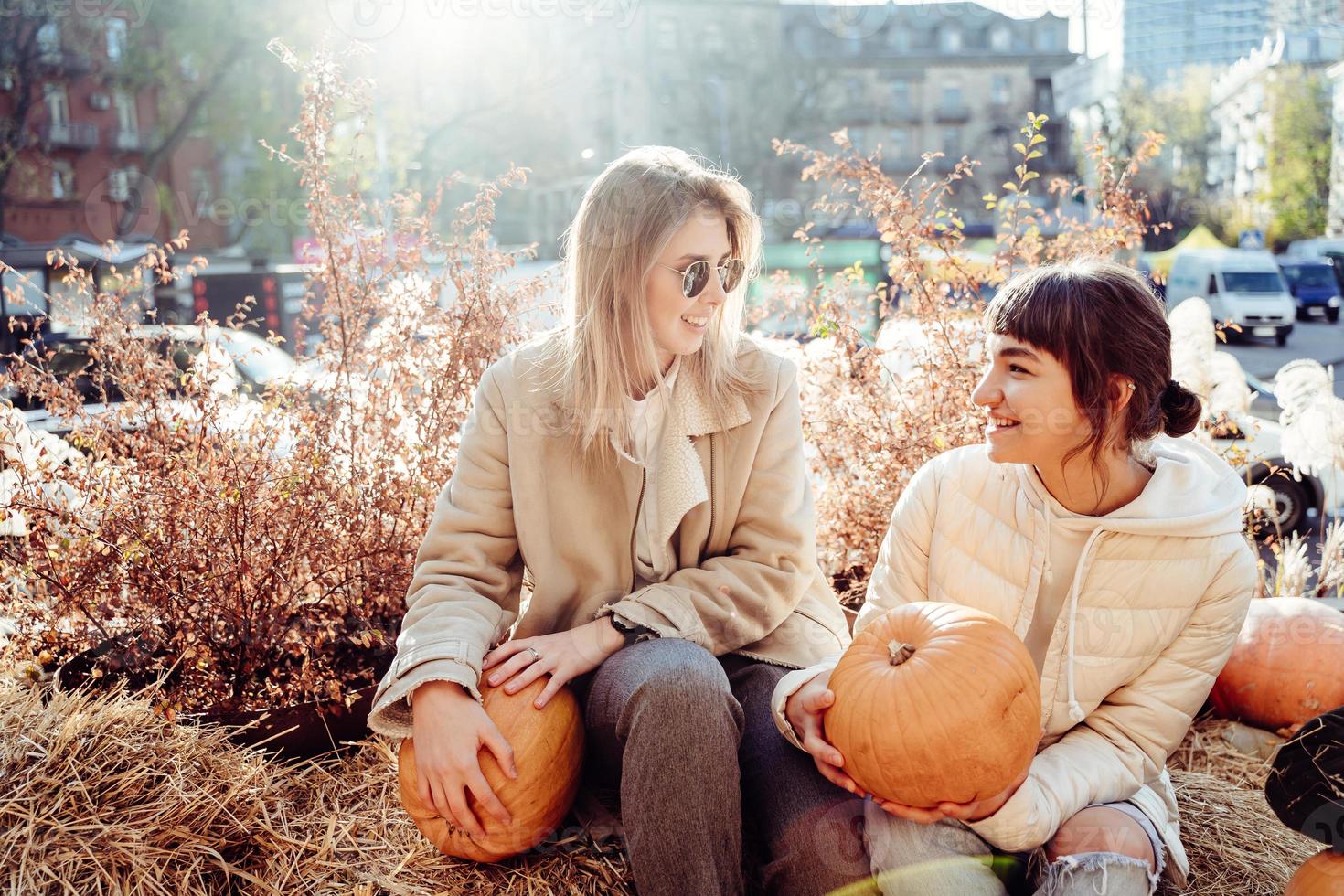 Girls holds pumpkins in hands on the background of the street. photo