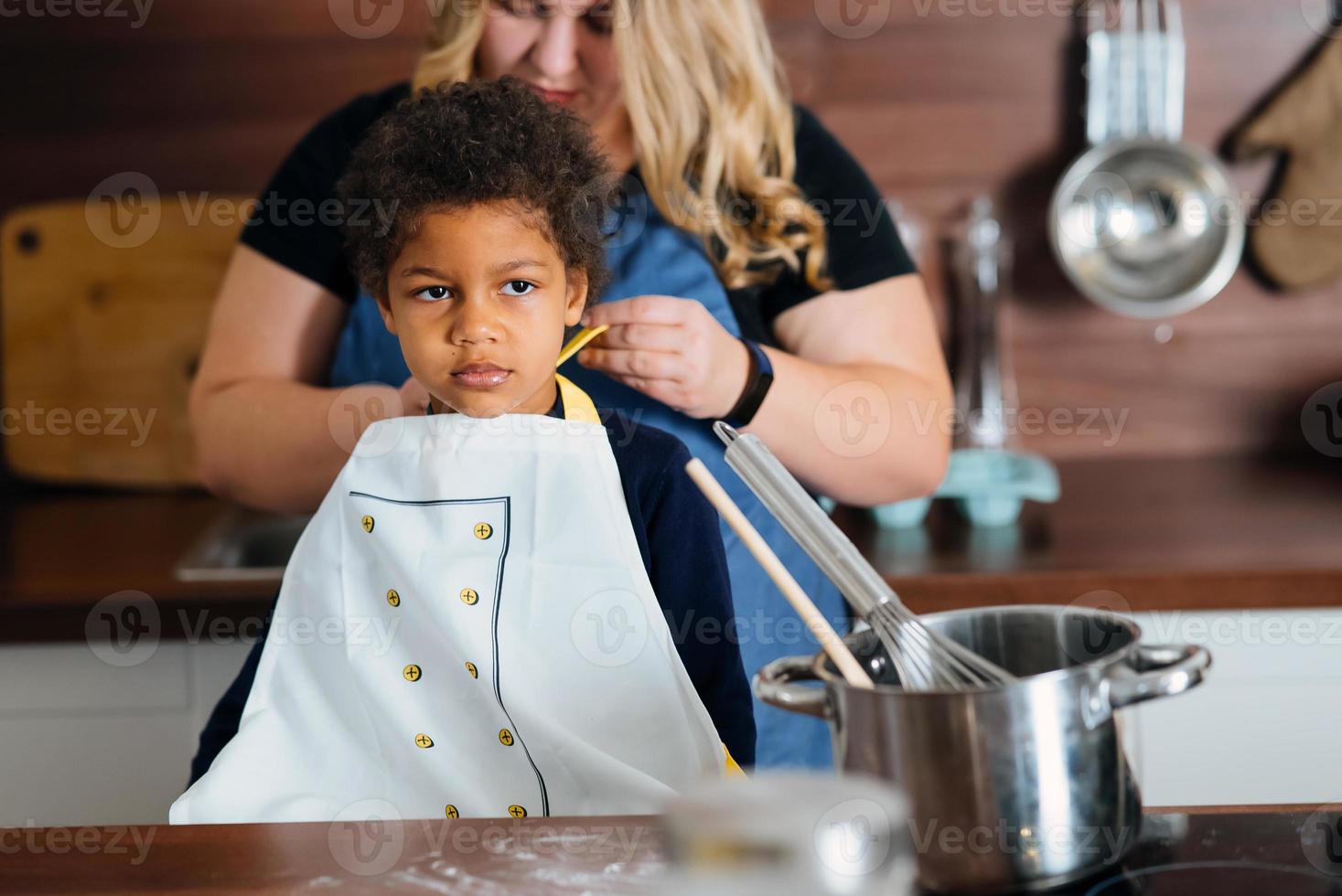 Mom ties an apron to her daughter in the kitchen photo