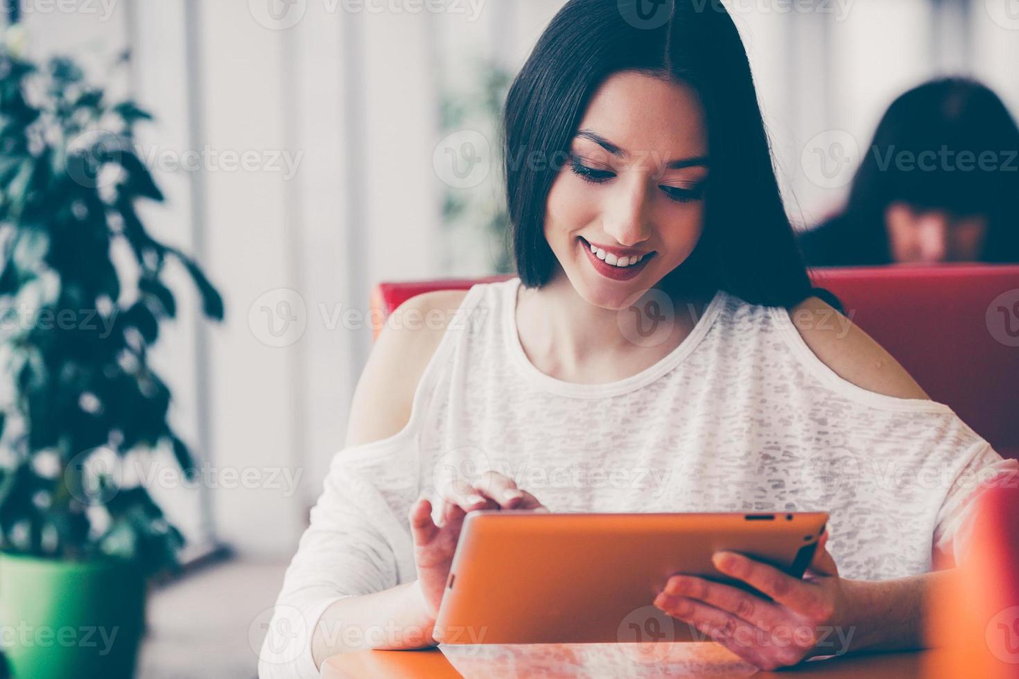 Beautiful girl working on a tablet and smiling photo