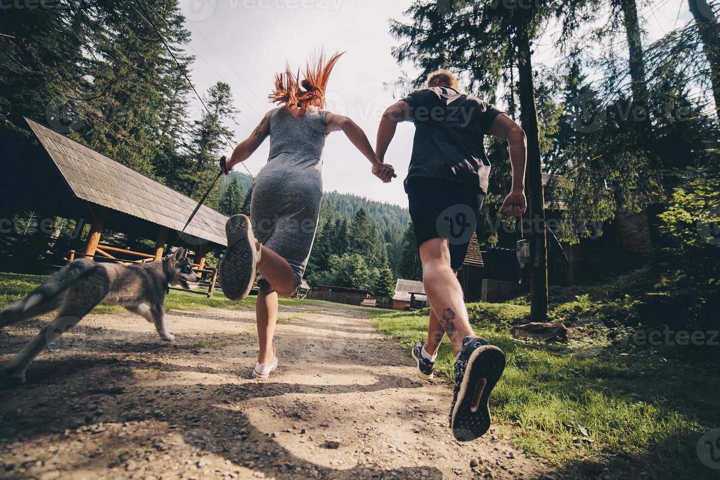 couple runs on road in the nature with dog photo