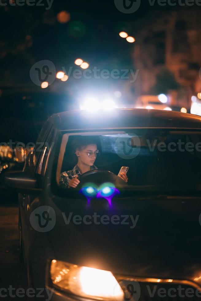 mujer conductora perdida que usa el teléfono móvil mientras conduce de noche. foto