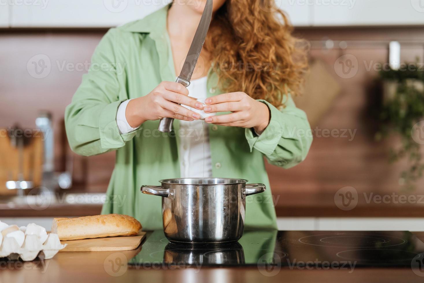 mujer joven está preparando comida en la cocina. batiendo huevos. foto