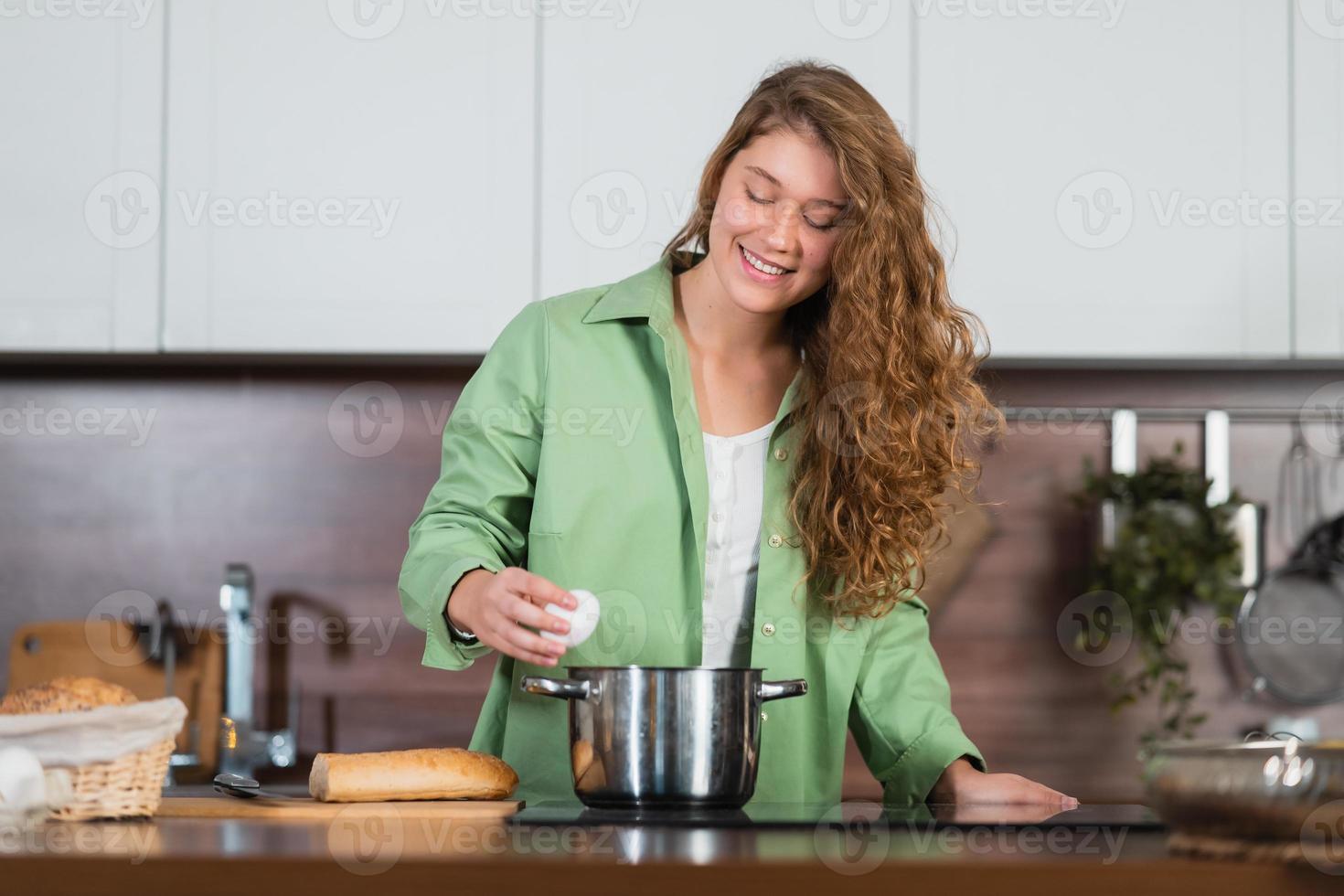 mujer joven está preparando comida en la cocina. batiendo huevos. foto