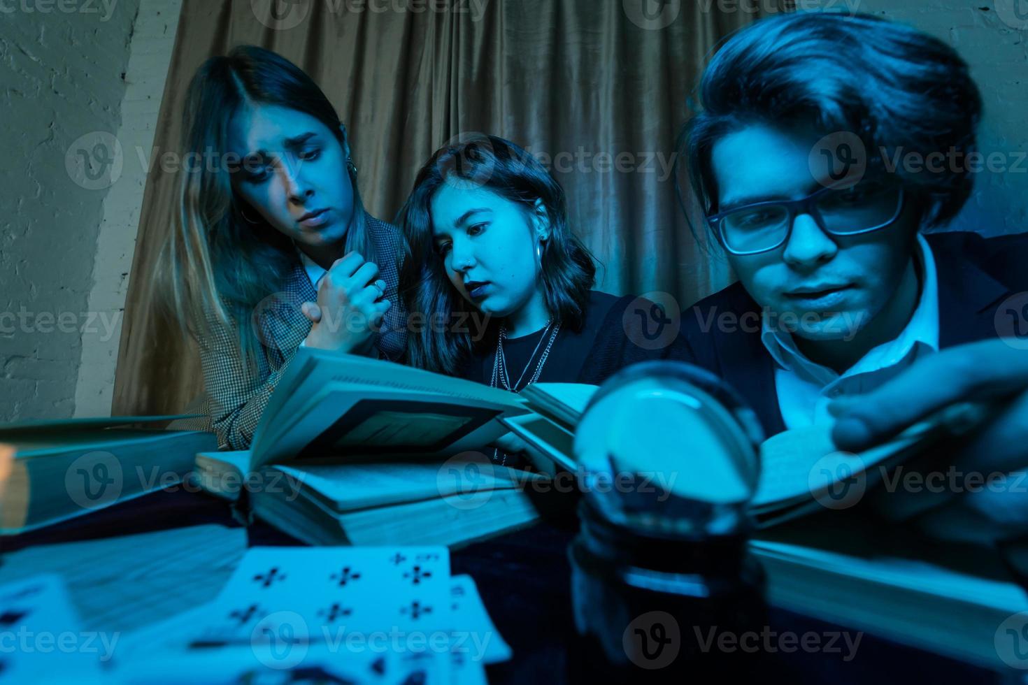 Two women and a guy are reading a mysterious books, close view photo