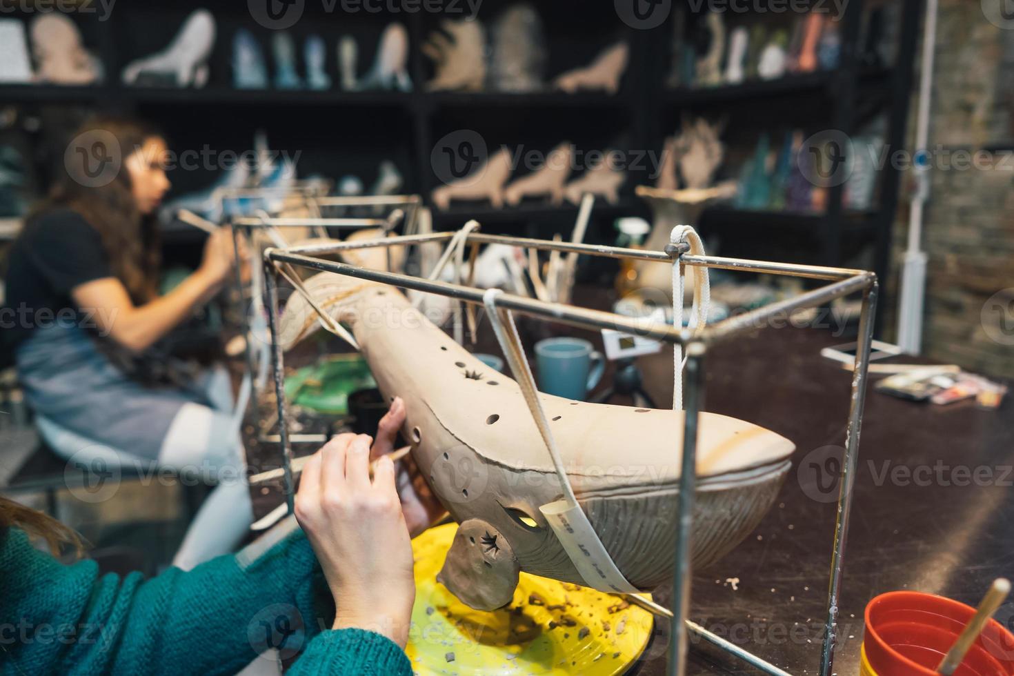 People carefully work on clay whales in workshop photo