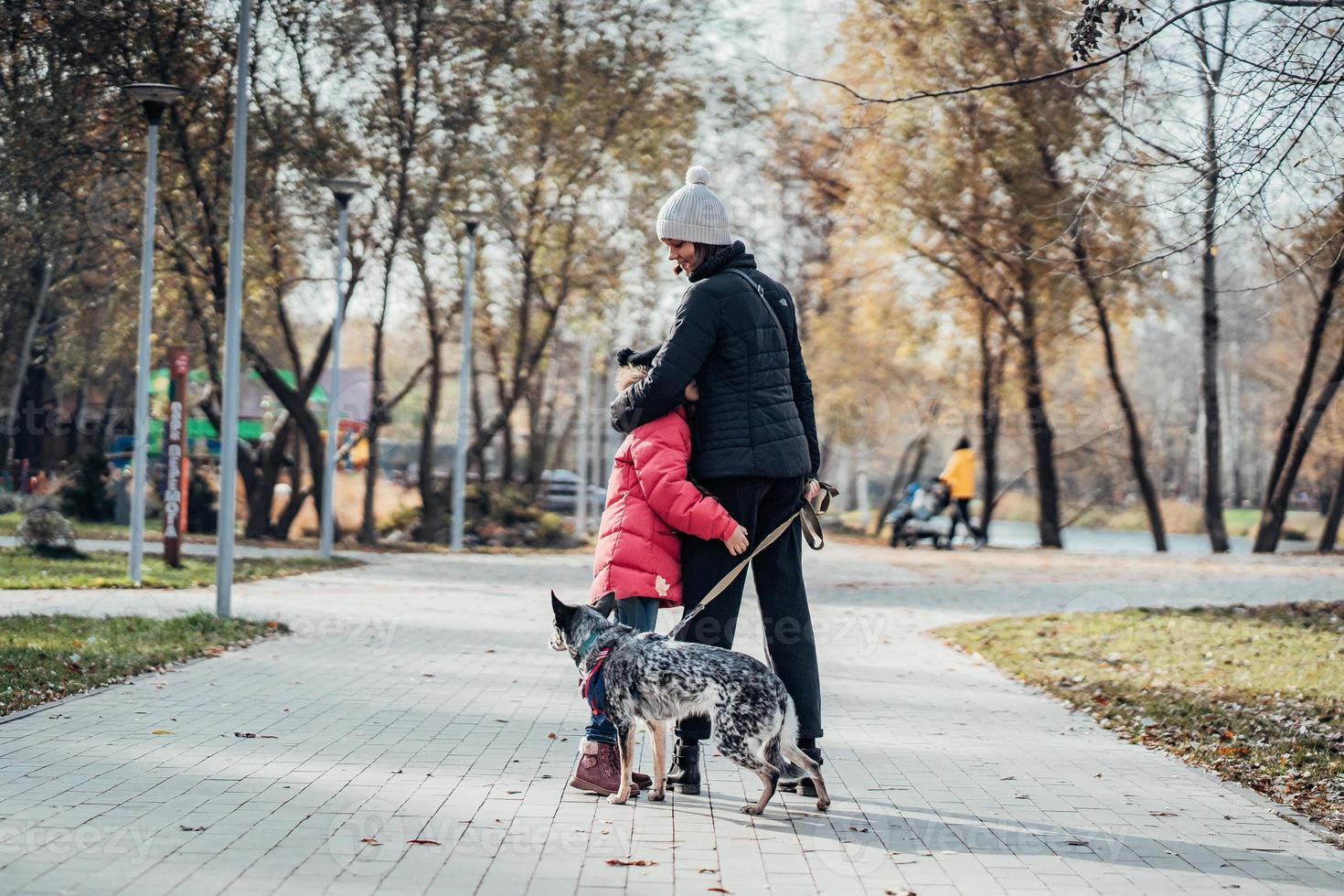 Happy mother and her daughter walk with dog in autumn park photo