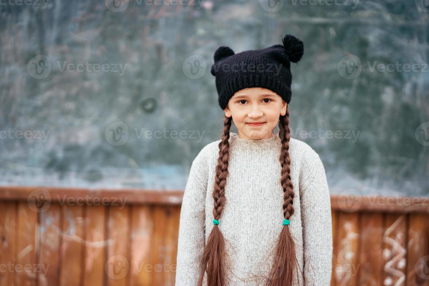 Little girl in a hat posing on the background of the school blackboard photo