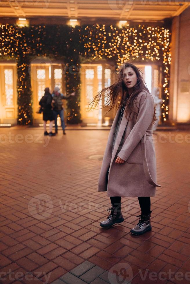 Girl on the background of the illuminated entrance to the building photo