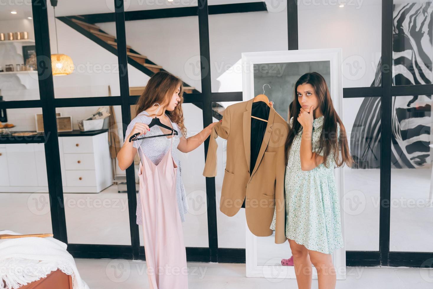 Two women choose and try on clothes at home photo