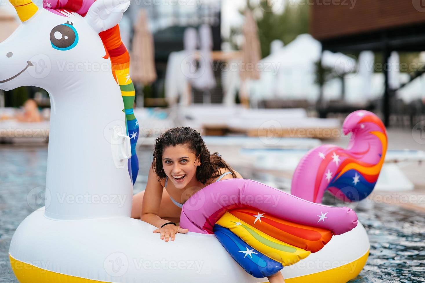 mujer en flotador inflable de colchón de juguete de unicornio en la piscina. foto