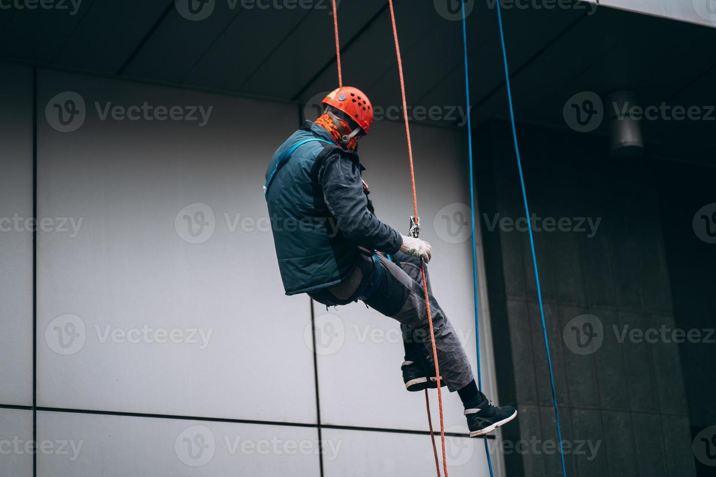 Industrial climber in uniform and helmet rises photo