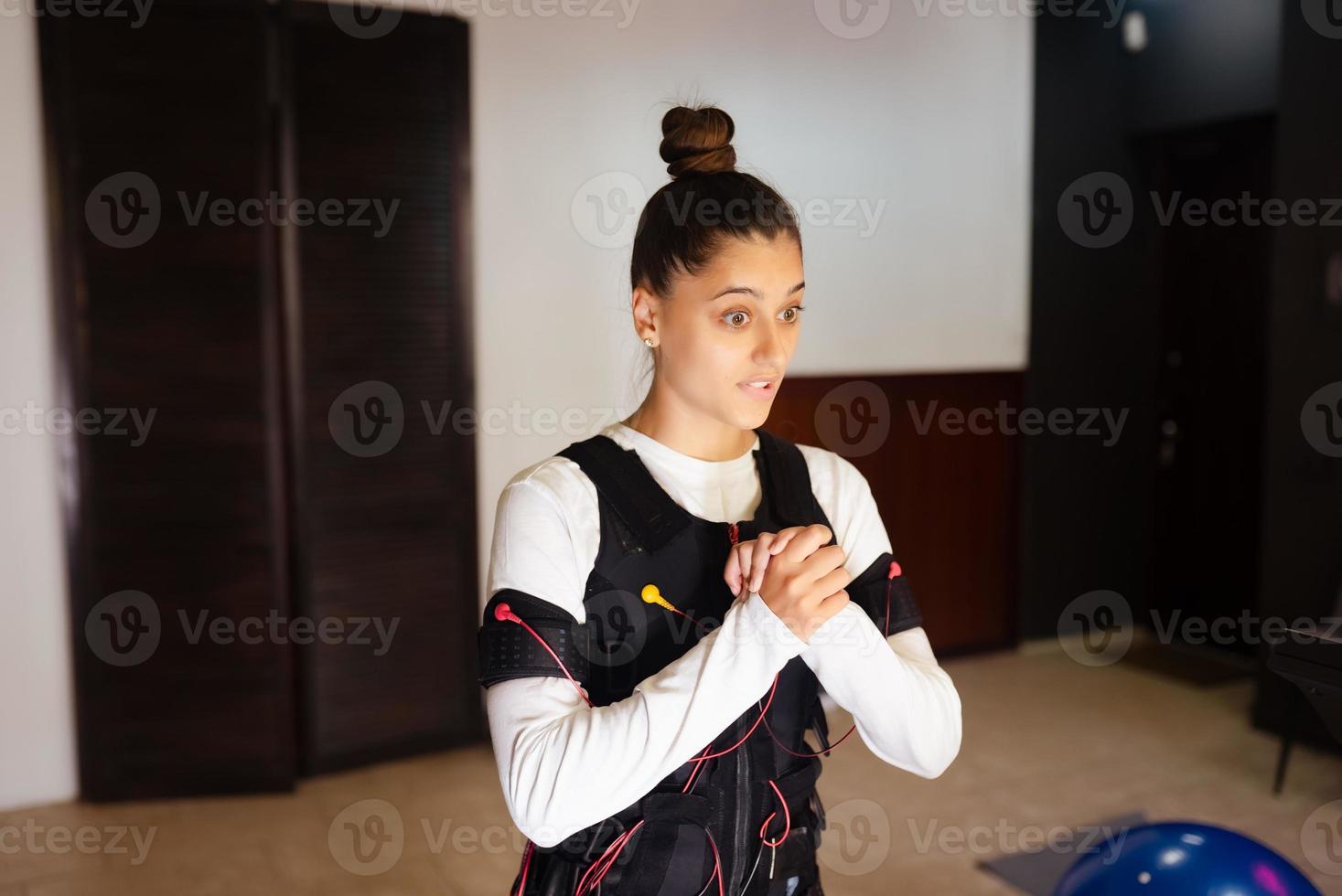 entrenamiento ems. chica haciendo ejercicios en un traje con cables. foto