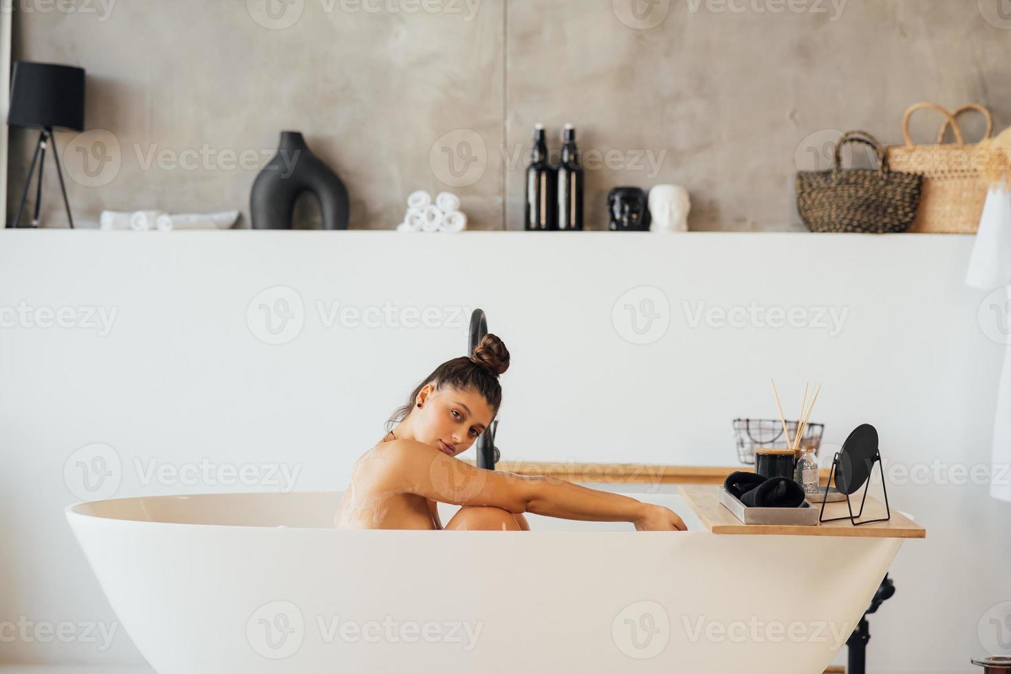 Side view of a woman taking a foam bath at home photo